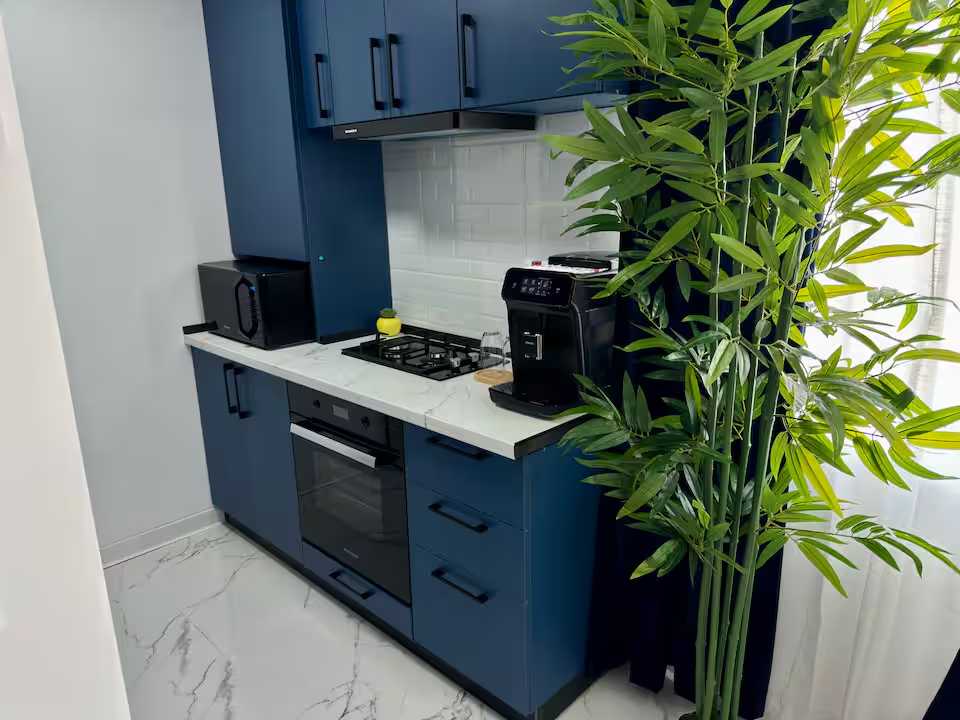 Una cucina con un forno nero e un piano di lavoro bianco — monolocale a Pitesti