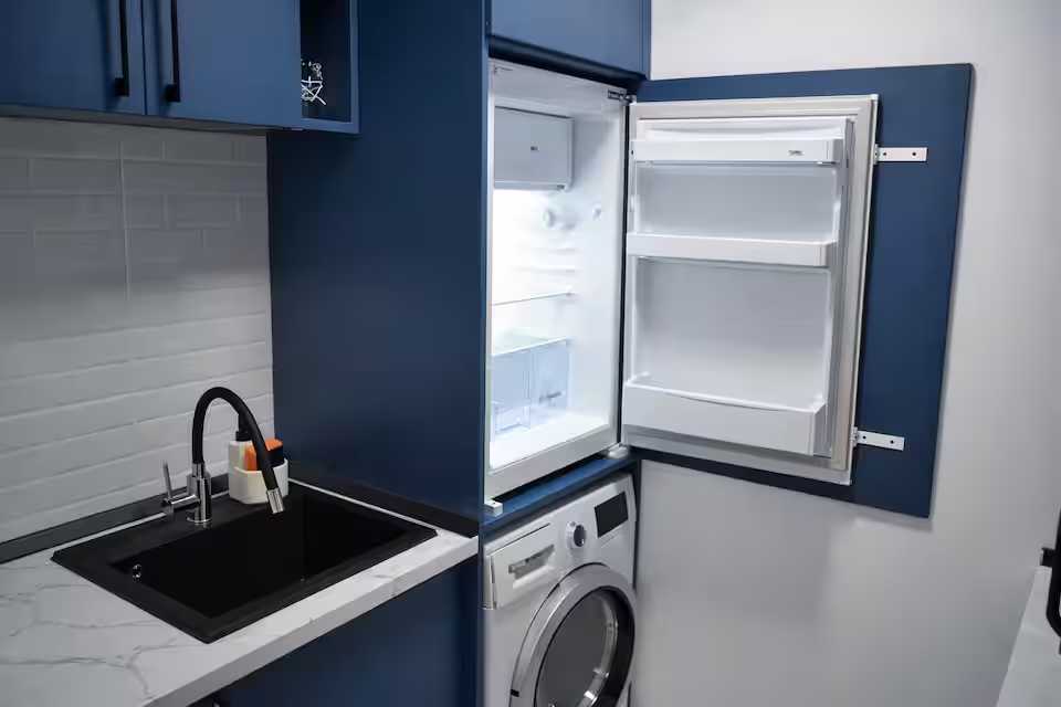 Una piccola cucina con lavello nero e frigorifero blu — monolocale a Pitesti