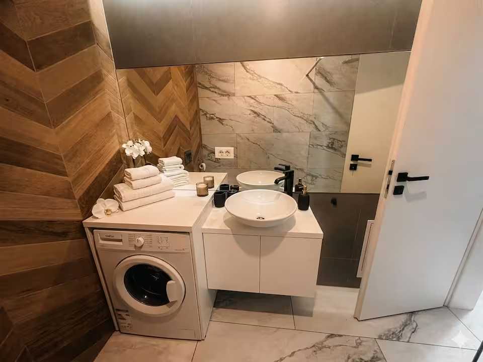 Un bagno con lavandino bianco, lavatrice e specchio — appartamento a Oradea
