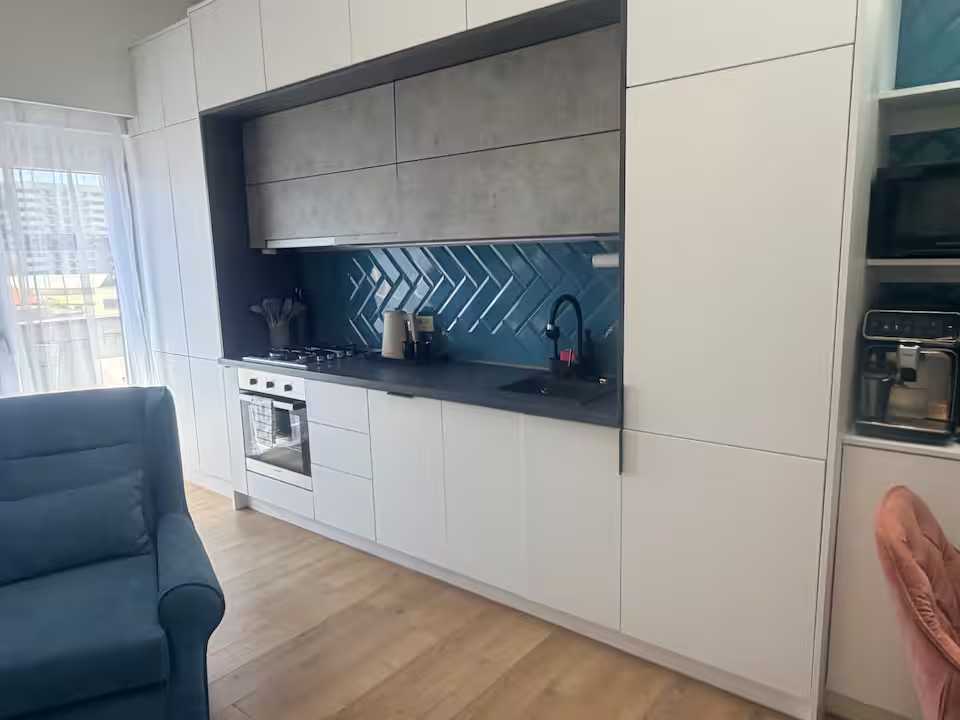 Una cucina con un forno e un divano blu — appartamento a Oradea