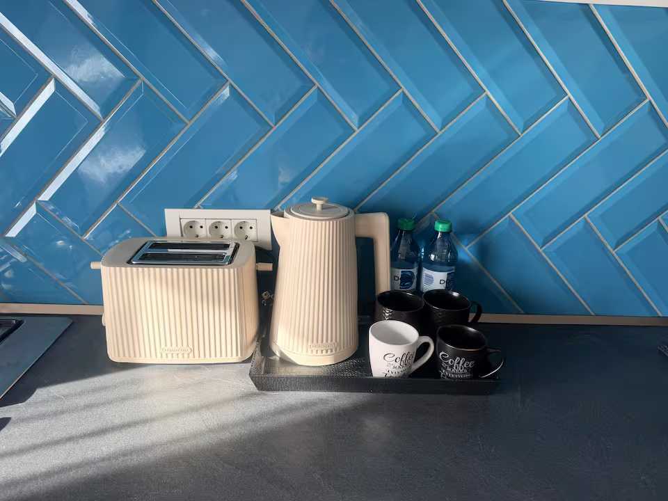 Una cucina con una macchina per il caffè, un bollitore per il tè e bottiglie d'acqua — appartamento a Oradea