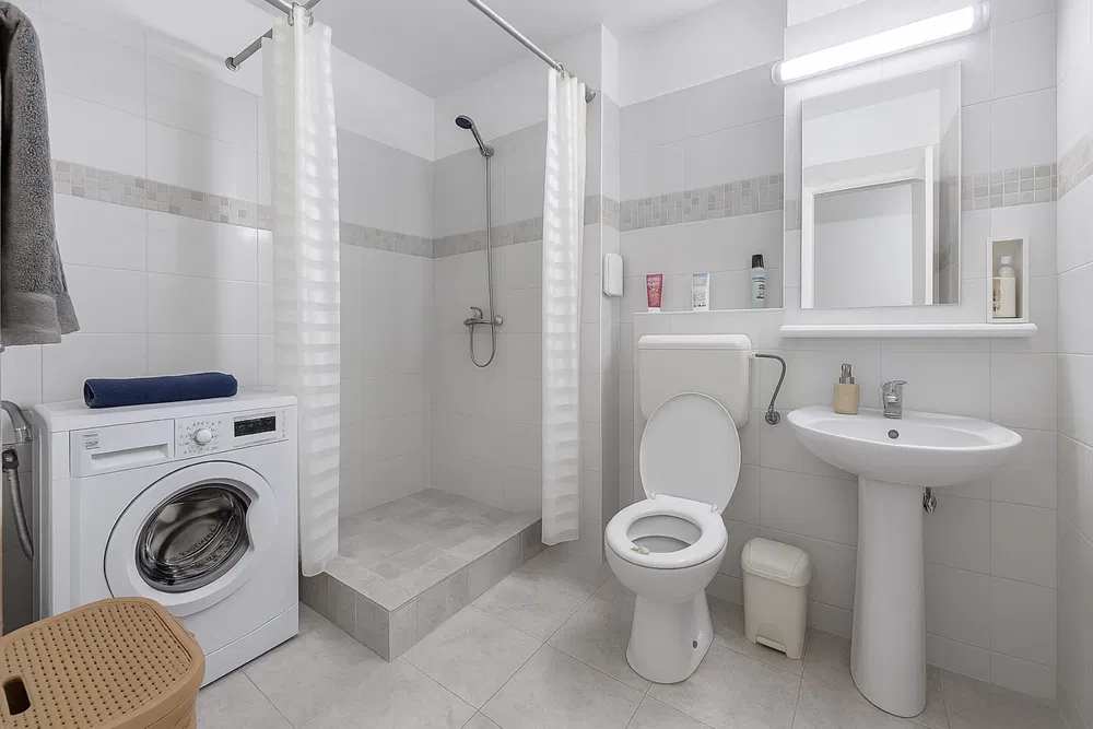 Un bagno bianco con bagno, lavanderia e lavanderia