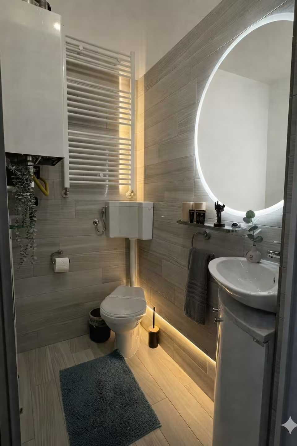Un bagno con wc, lavandino, specchio e tappeto blu — monolocale a Oradea