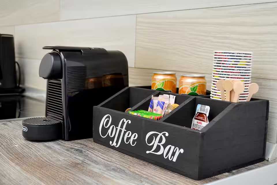 Un bar caffè nero con una macchina da caffè e lattine di caffè — monolocale a Oradea
