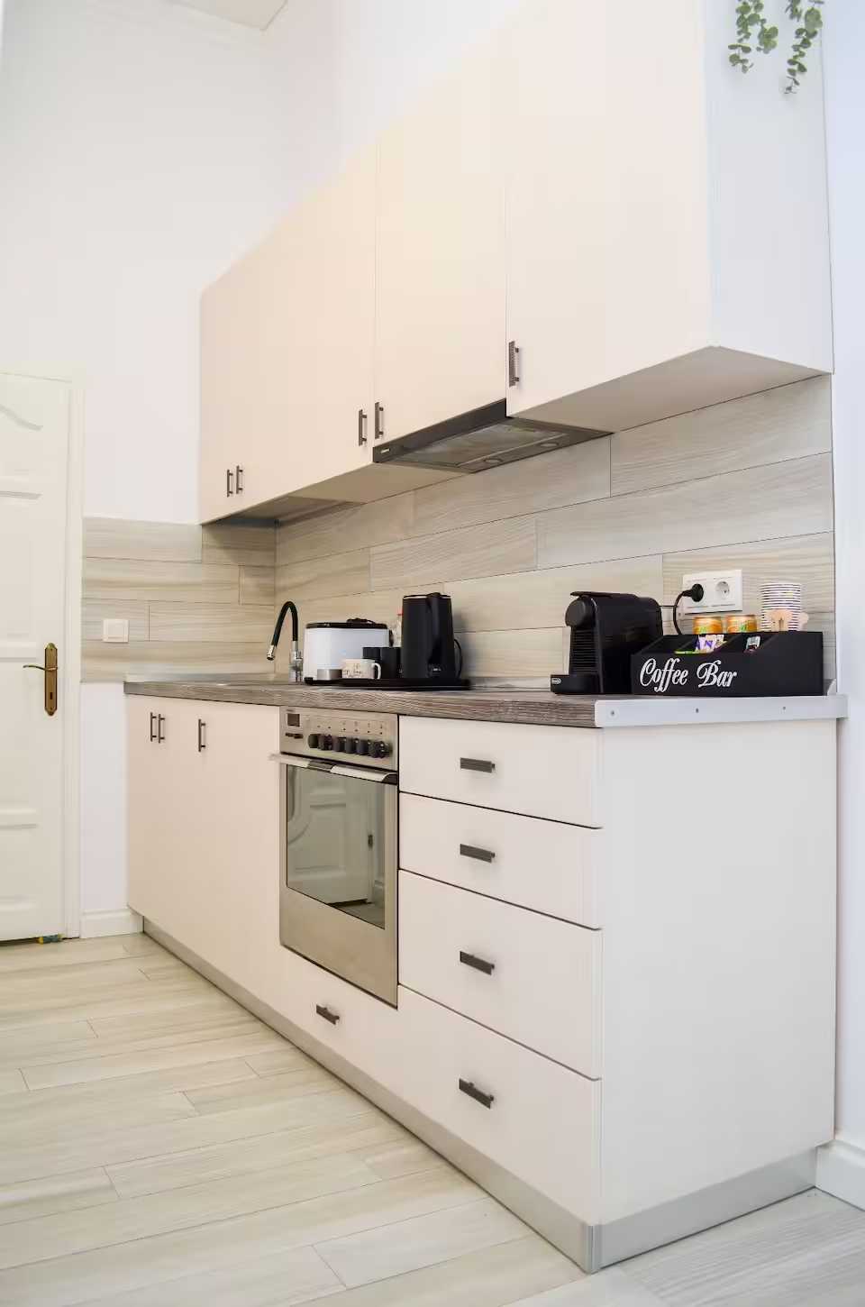 Una cucina con forno bianco, mobili bianchi e macchina da caffè — monolocale a Oradea