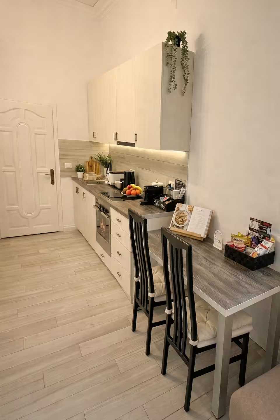 Una cucina bianca con tavolo e sedie — monolocale a Oradea