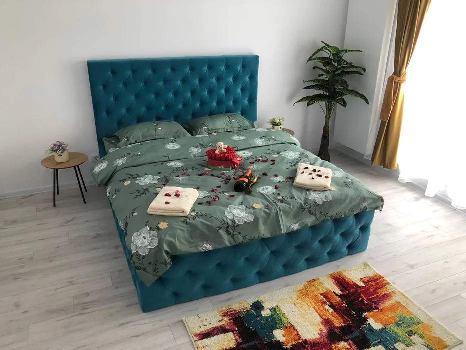 Una camera con un letto blu e una finestra — monolocale a Brașov