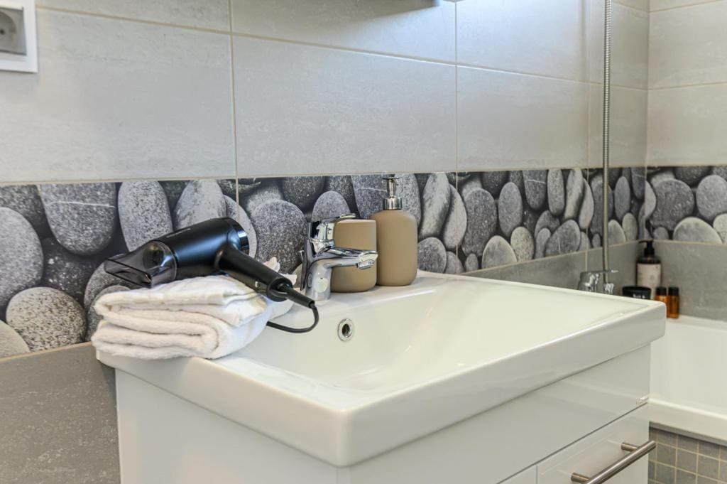 Un bagno con un lavandino e un asciugacapelli — appartamento a Brașov
