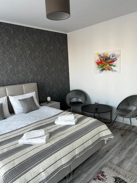 Una camera con un letto, una sedia e un quadro al muro — appartamento a Brașov