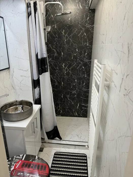 Un bagno con una cortina da doccia bianca e uno scaffale di asciugamani bianchi