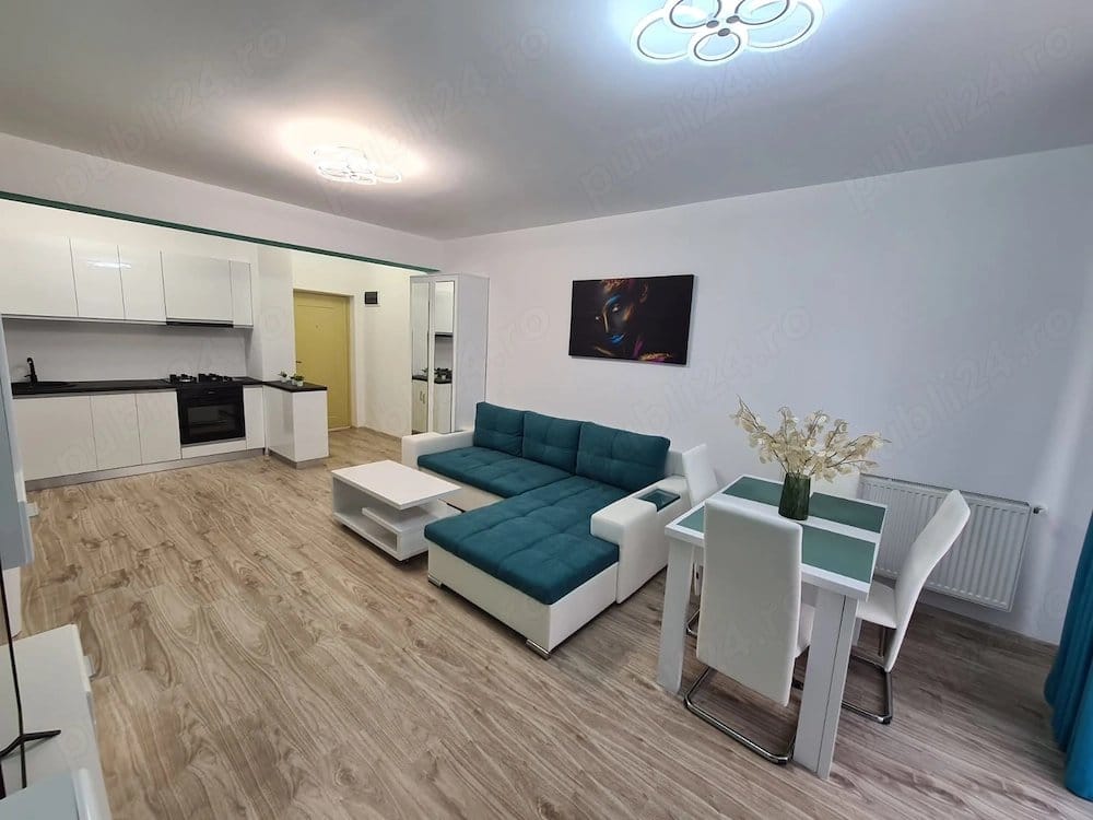 A living room with a couch, table, and a view of the kitchen