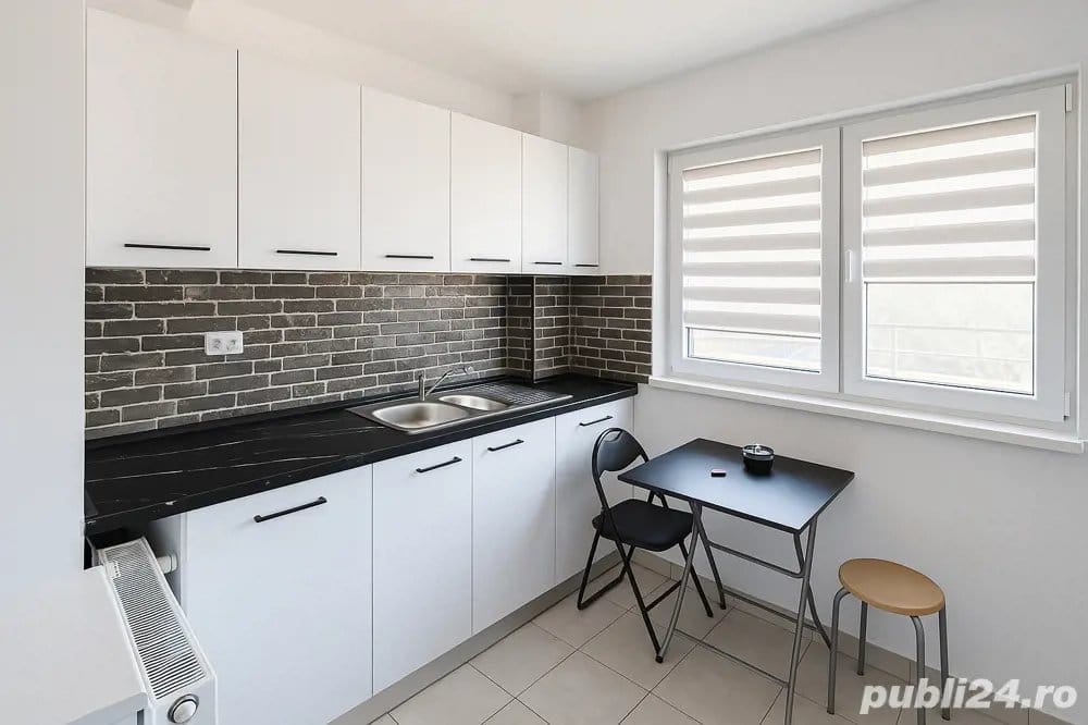 Una piccola cucina pulita, bianca, con un top nero e una finestra