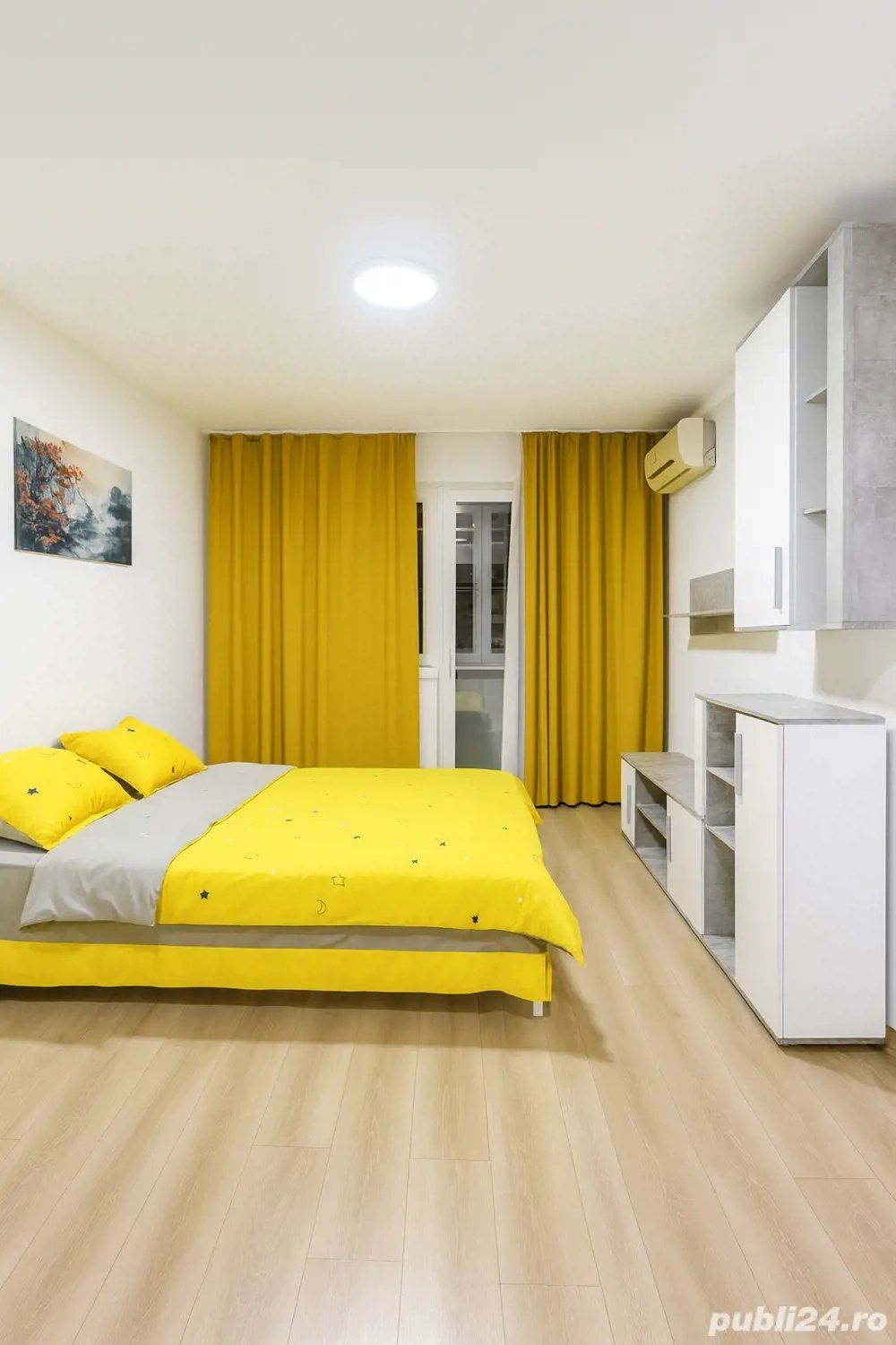Una stanza con un letto, una finestra e una cortina gialla