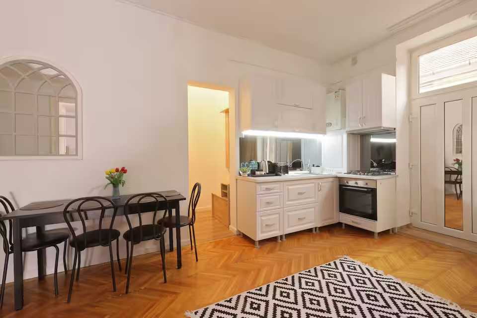 Una cucina con mobili bianchi e un tavolo — appartamento a Oradea
