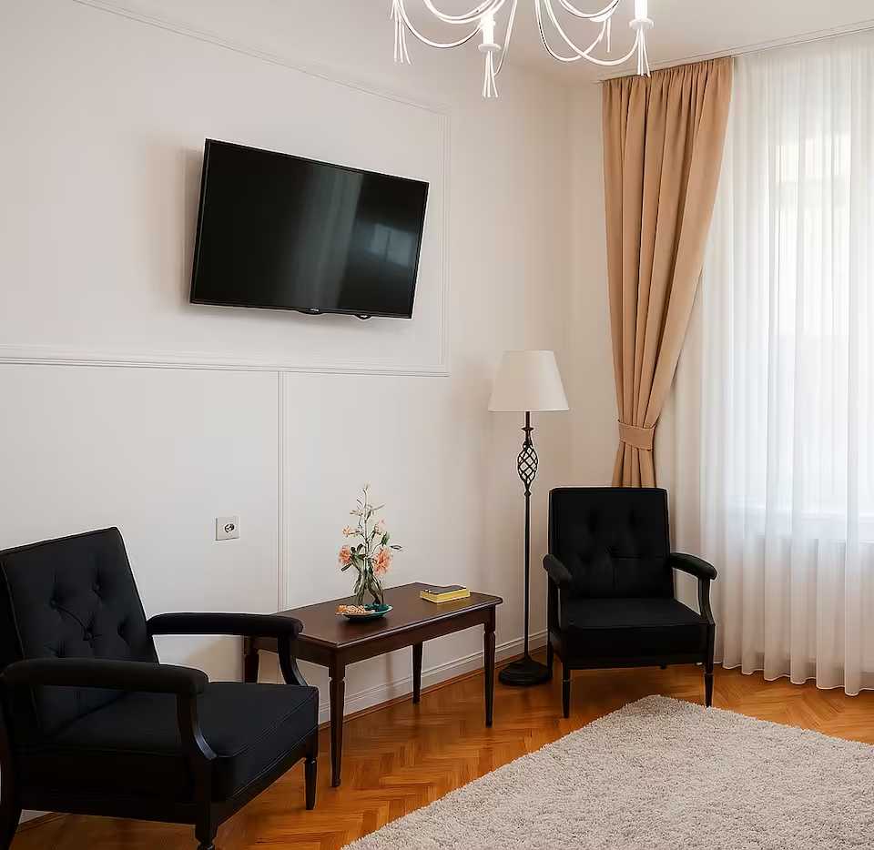 Una stanza con TV a schermo piatto, un tavolo, una sedia e una finestra — appartamento a Oradea