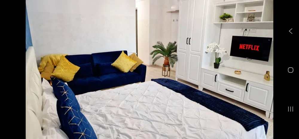 Un divano blu con cuscini gialli e un letto blu con un confortatore bianco
